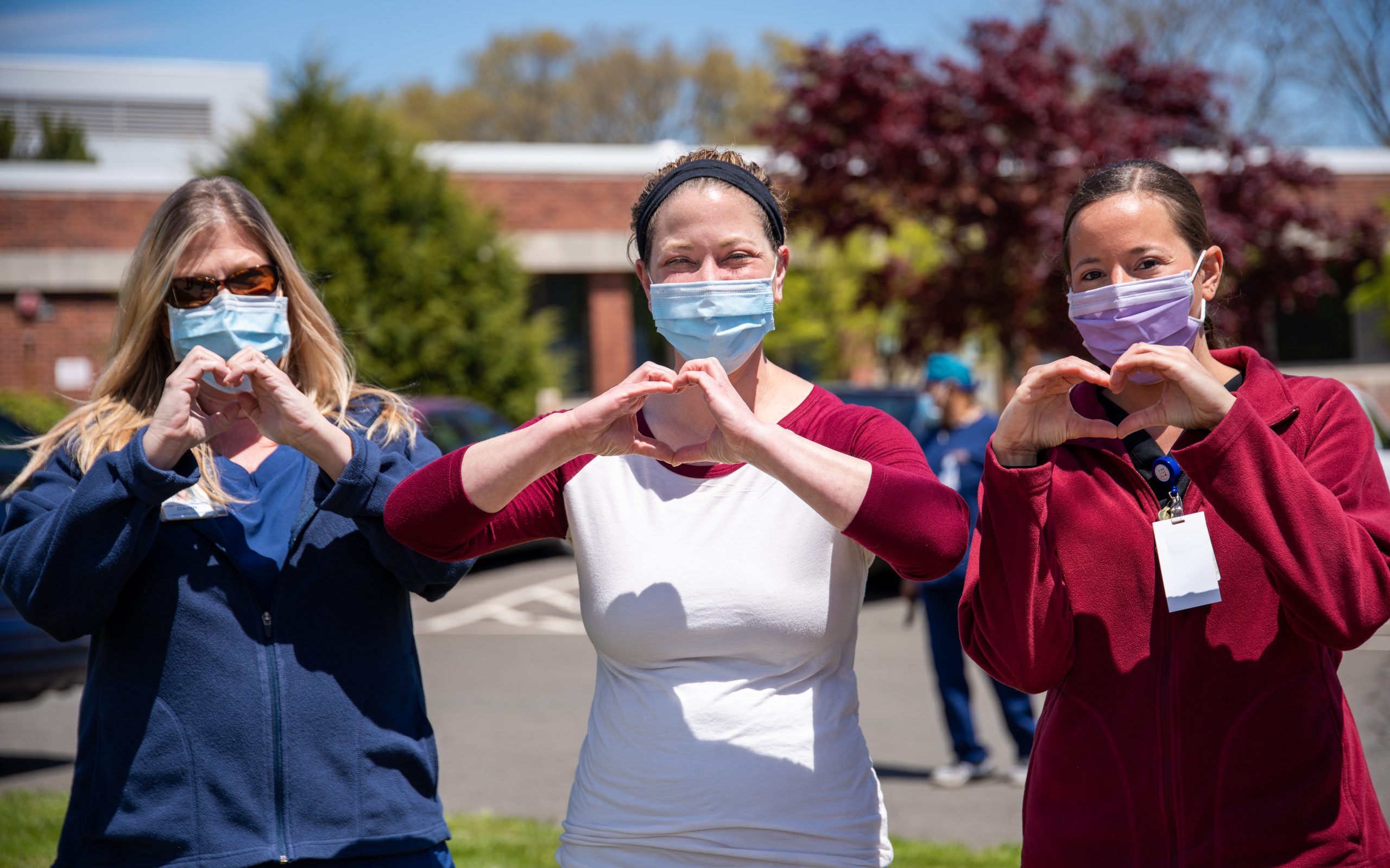 Three care workers making heart signs with their hands