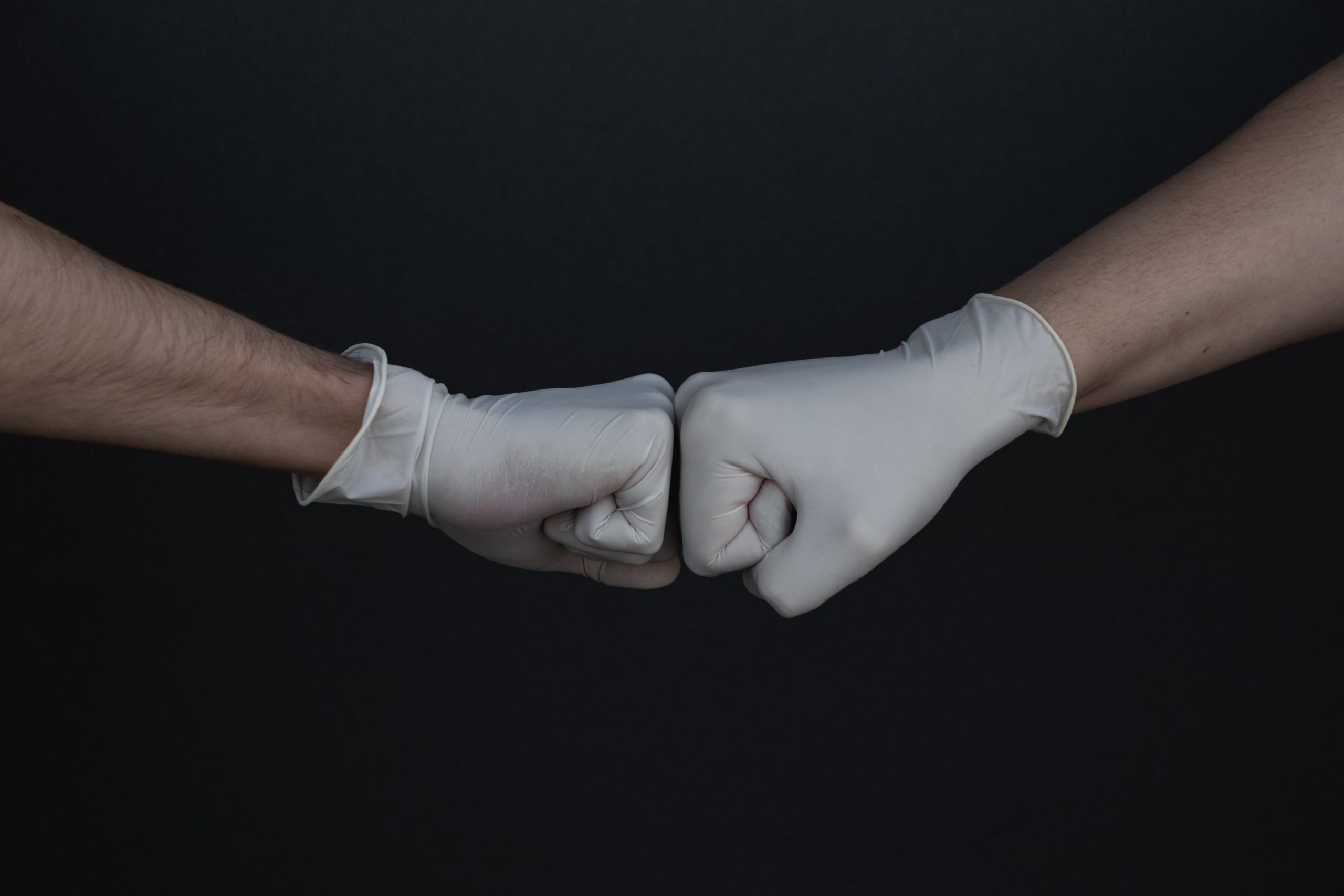 A fist bump between people wearing gloves